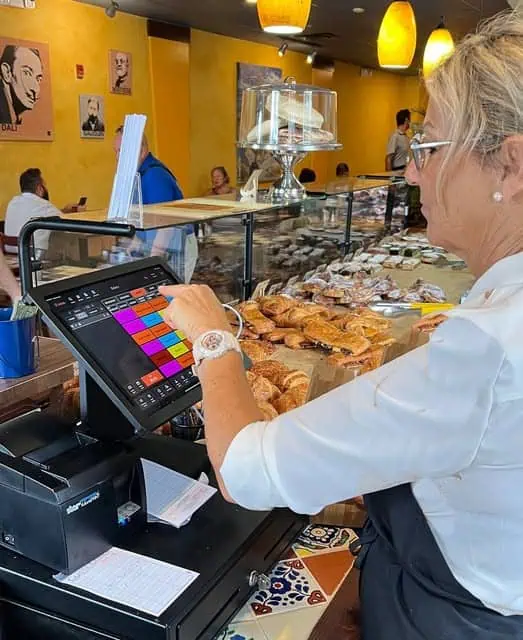 Waiter using Card Systems POS touchscreen to manage orders at a restaurant in Florida.