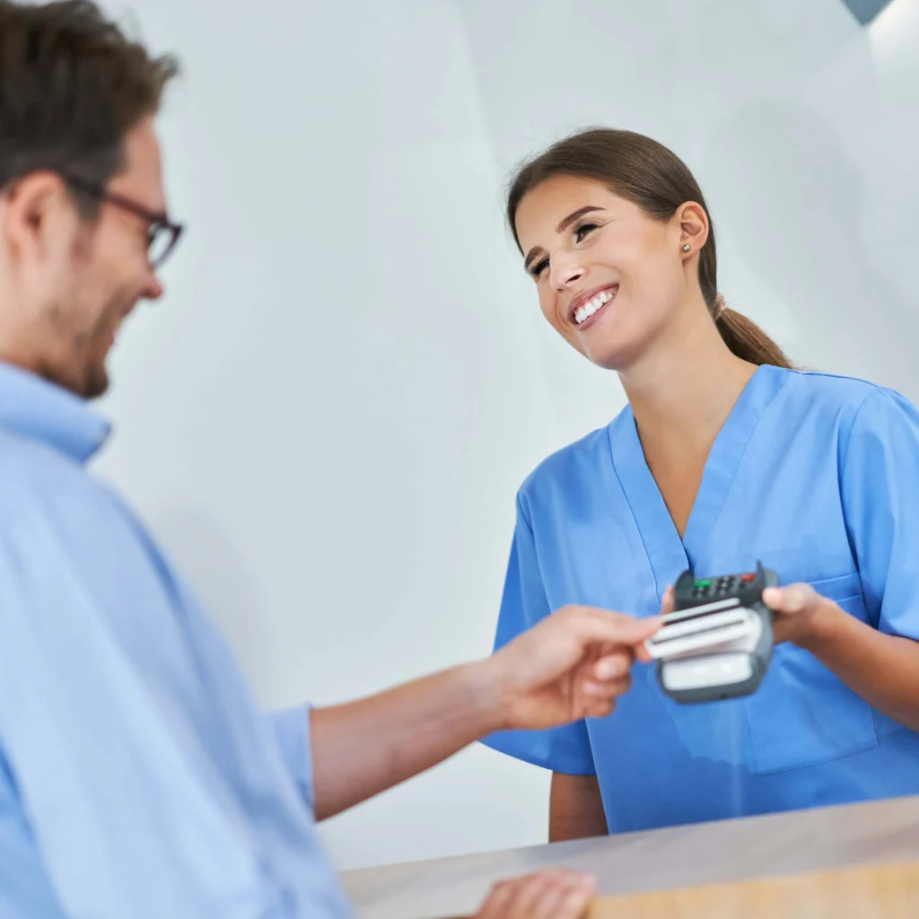 Patient using Buy Now, Pay Later payment option at a Florida medical practice checkout with a smiling receptionist.