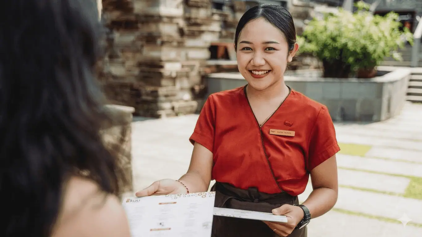 Server handing clean menus to a restaurant guest during a welcoming first impression