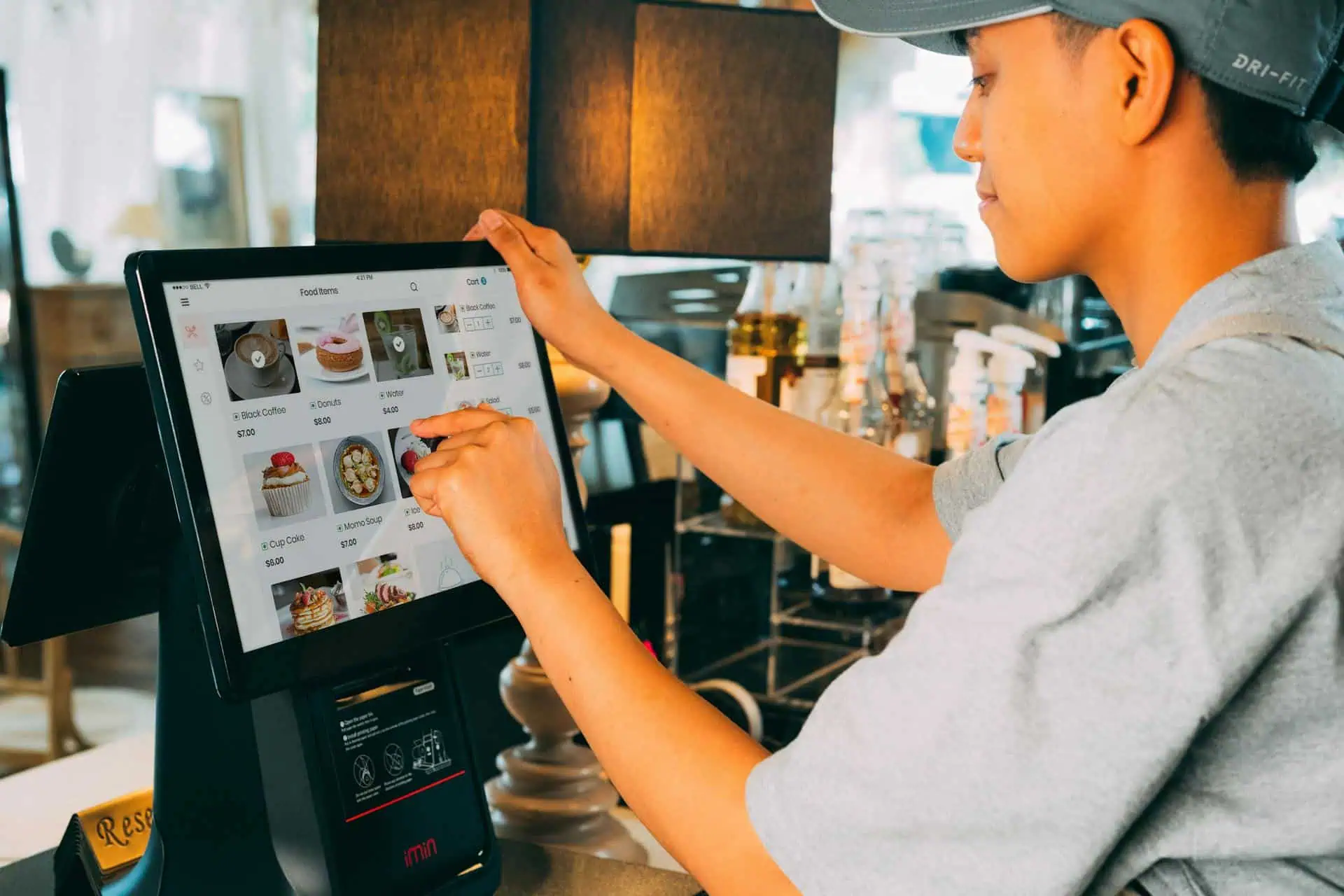 Restaurant employee using touchscreen POS to enter online food orders
