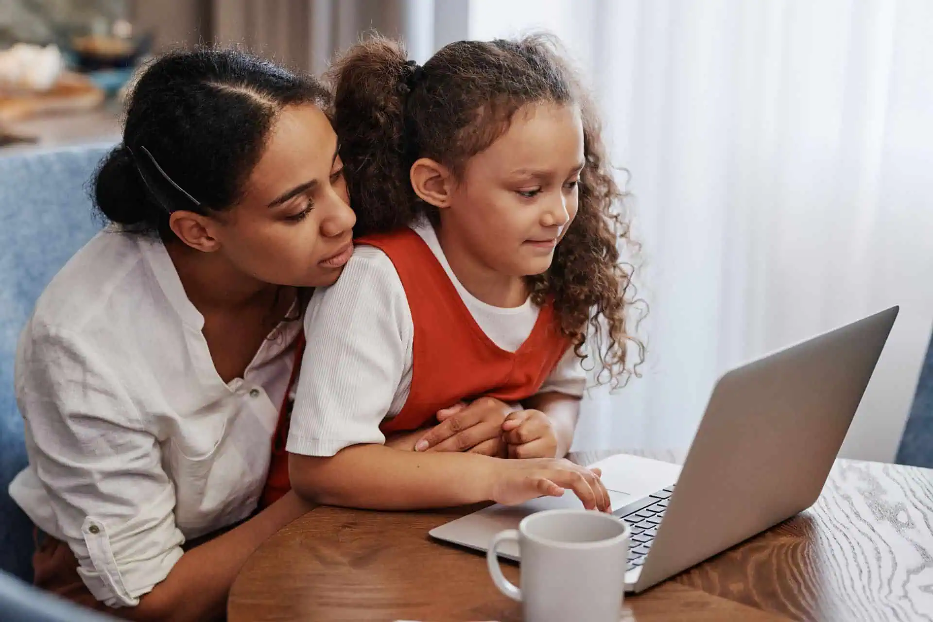 Mother and daughter using a laptop together while learning about family business payroll and money management.