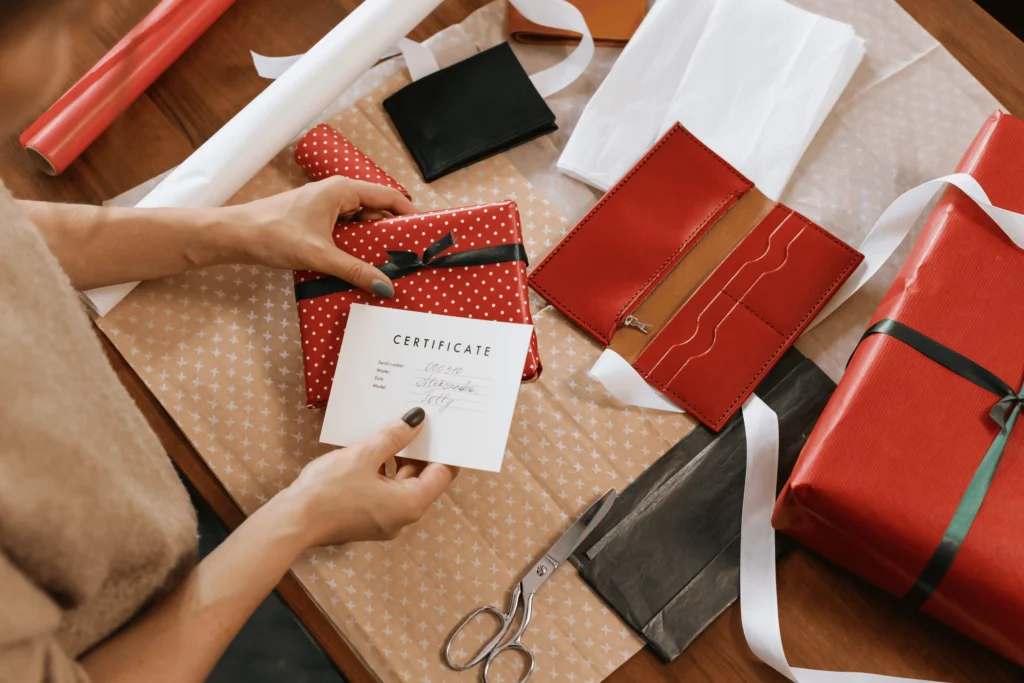 Blank white card beside a small gift box with a red ribbon on a peach background